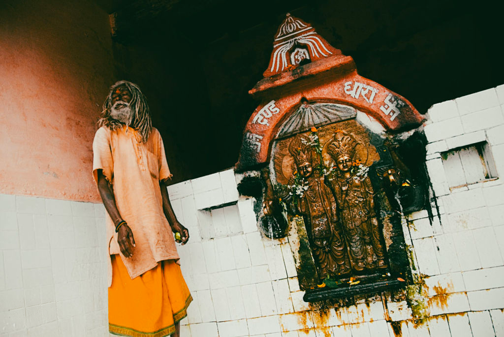 Standing sadhu beside a shrine